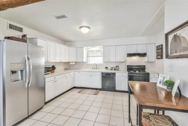 a kitchen with a refrigerator a stove a sink dishwasher and white cabinets with wooden floor