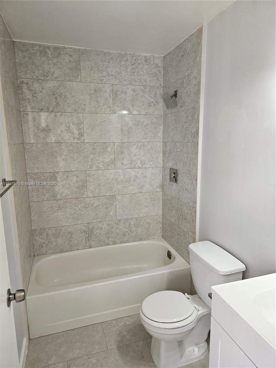 5849 Wiley Street, Unit 2 Hollywood, FL 33023 - Photo 3 of 10 a white toilet and tub sitting next to a bathroom sink