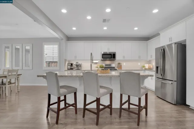 a kitchen with kitchen island white cabinets and stainless steel appliances