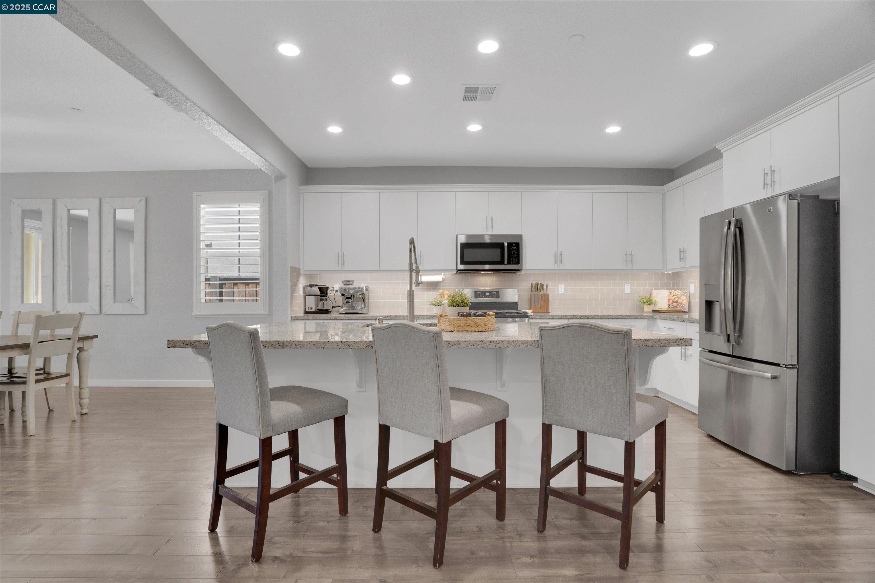 a kitchen with kitchen island white cabinets and stainless steel appliances