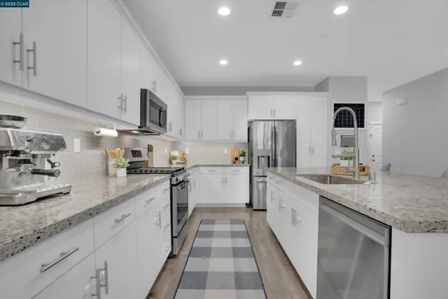 a large kitchen with stainless steel appliances lots of counter space and a sink