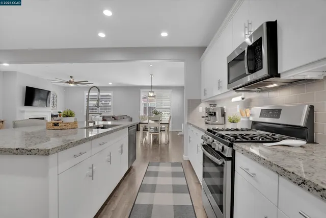 a kitchen with stainless steel appliances granite countertop a stove a sink and a microwave