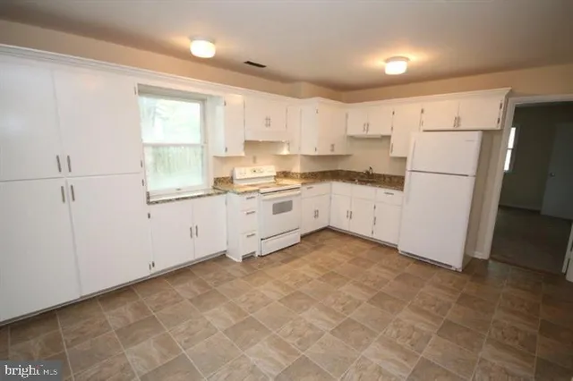 a kitchen with white cabinets and white appliances