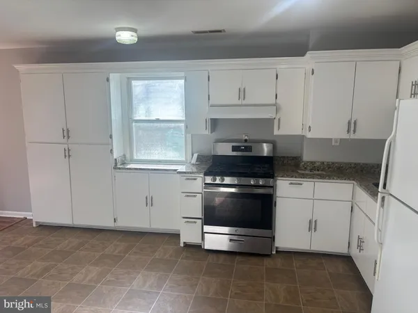 a kitchen with white cabinets and appliances