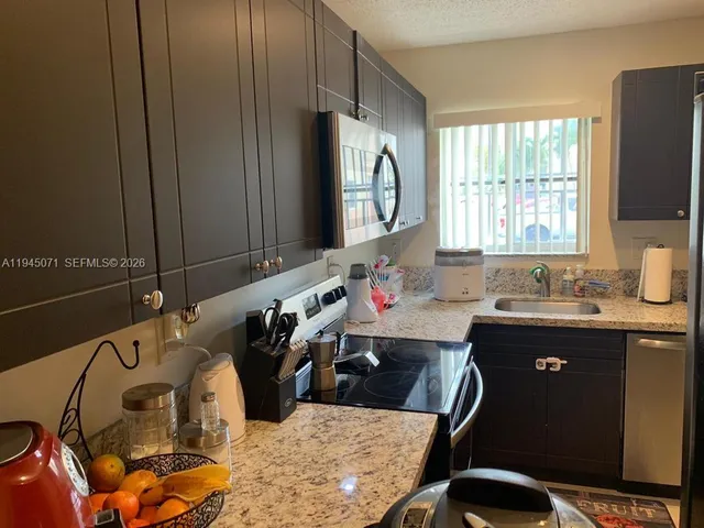 a kitchen with stainless steel appliances granite countertop a stove top oven microwave and cabinets