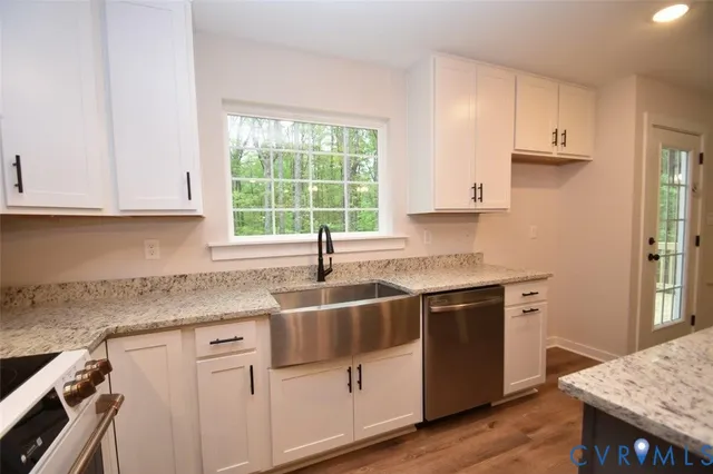 a kitchen with granite countertop a sink stove and cabinets