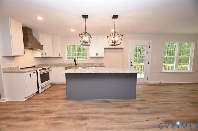 a kitchen with stainless steel appliances granite countertop a sink a stove and a wooden floors