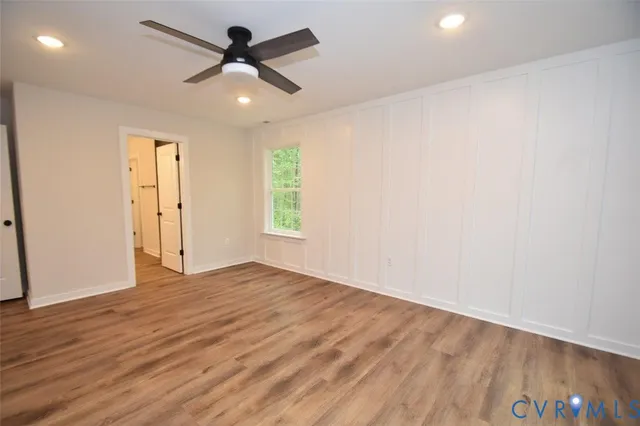 an empty room with wooden floor ceiling fan and windows