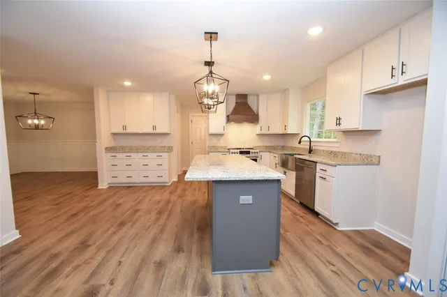a kitchen with kitchen island granite countertop a sink cabinets and wooden floor