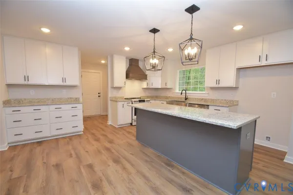 a large kitchen with granite countertop a sink window and white cabinets