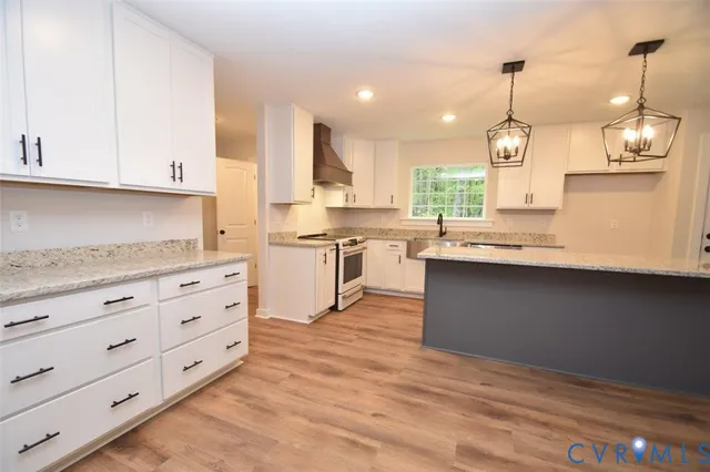 a kitchen with stainless steel appliances granite countertop a sink a stove and a wooden floors