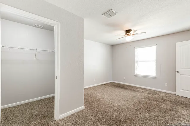 an empty room with windows and chandelier fan