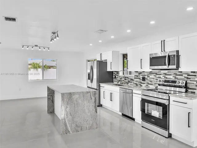 a kitchen with stainless steel appliances granite countertop a refrigerator sink and stove