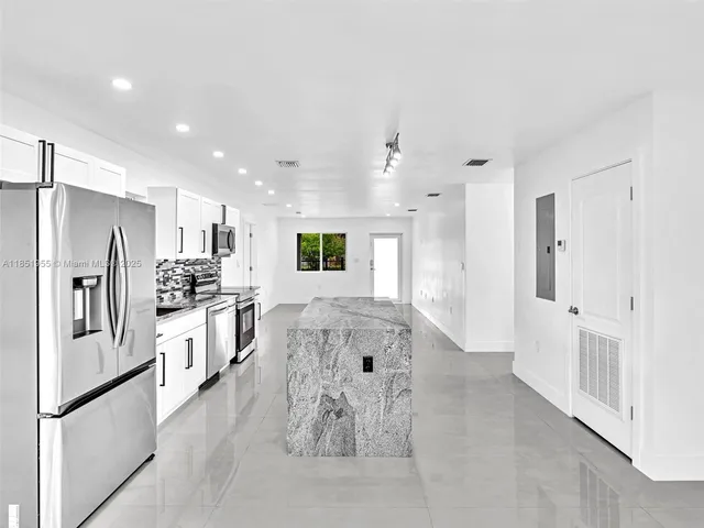 a kitchen with kitchen island white cabinets and stainless steel appliances