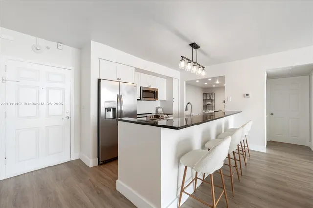 a kitchen with stainless steel appliances granite countertop a refrigerator oven a sink dishwasher and white cabinets with wooden floor