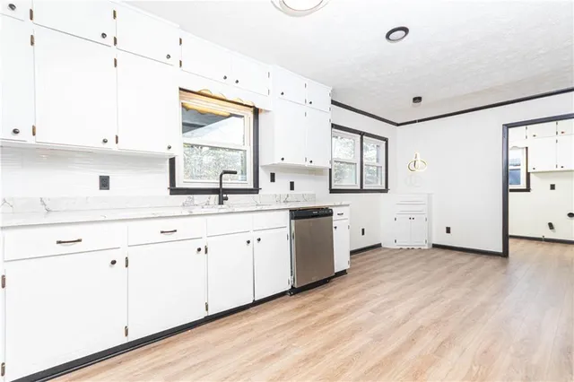 a large white kitchen with a lot of cabinets and wooden floor