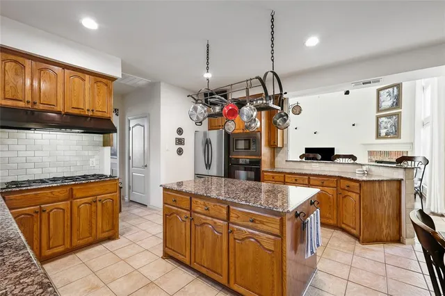 a kitchen with stainless steel appliances granite countertop a sink dishwasher stove and refrigerator with wooden cabinets