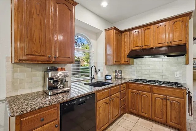 a kitchen with stainless steel appliances granite countertop a sink a stove and cabinets