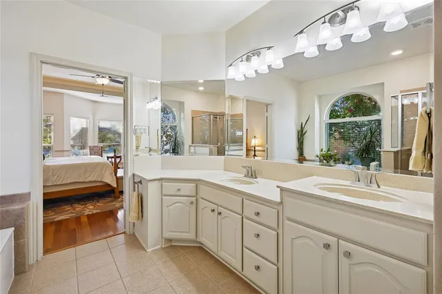 a spacious en suite bathroom with a sink a large mirror and a shower
