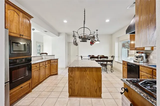 a kitchen with stainless steel appliances granite countertop a stove top oven a sink dishwasher a dining table and chairs with wooden floor