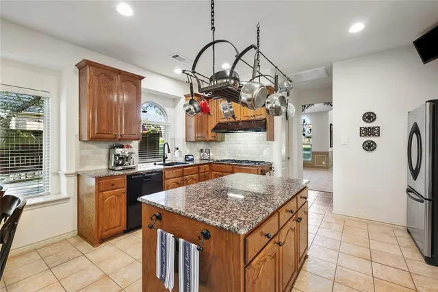 a kitchen with stainless steel appliances granite countertop a sink a stove and a refrigerator