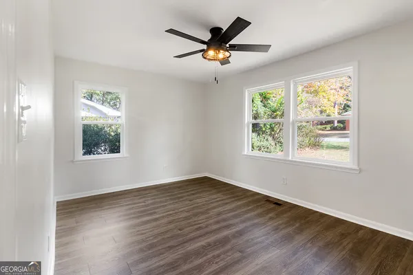 a view of an empty room with wooden floor and a window