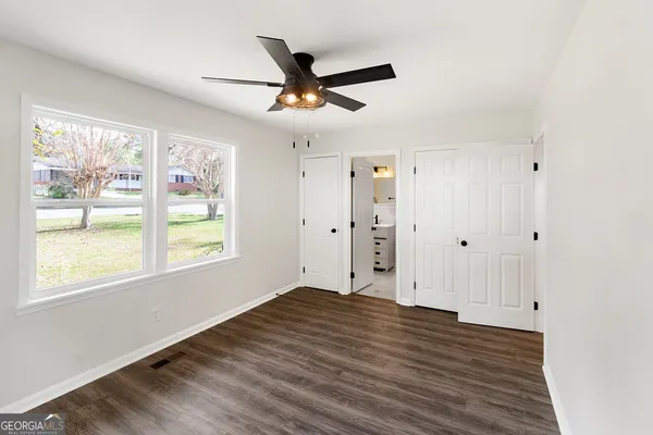 a view of an empty room with wooden floor and a window