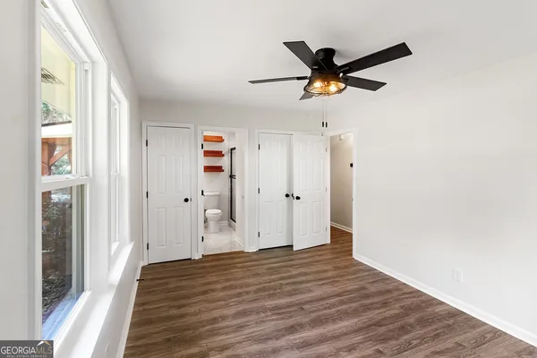 a view of empty room with wooden floor and ceiling fan