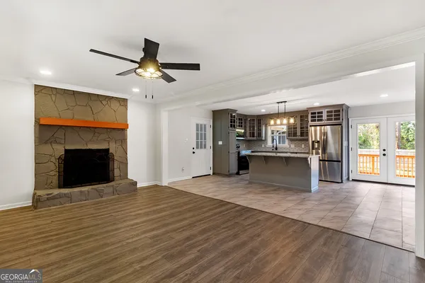 a view of an empty room with kitchen and fireplace