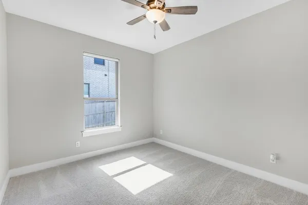 an empty room with chandelier fan and windows