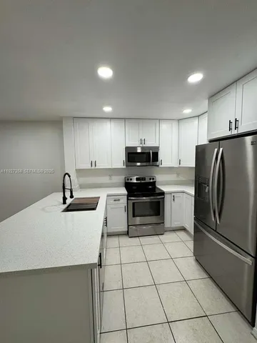 a kitchen with a sink a refrigerator and cabinets