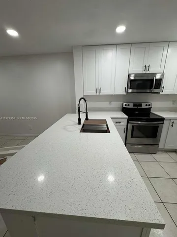 a kitchen with kitchen island a sink stainless steel appliances and cabinets