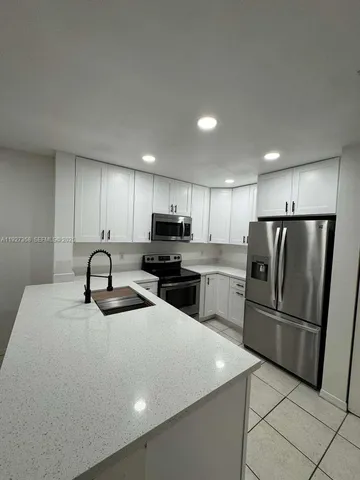 a kitchen with refrigerator a microwave and white cabinets