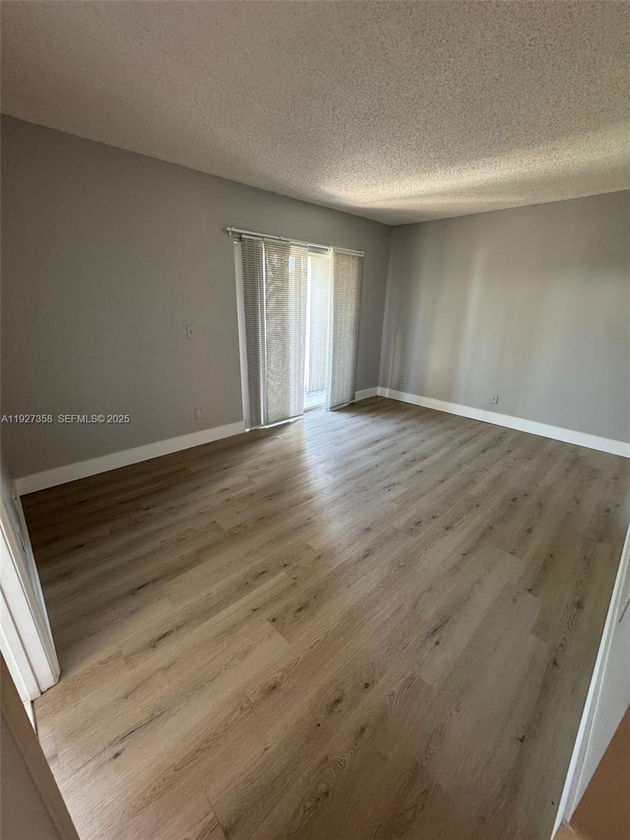 12605 Southwest 54th Court, Unit 12605 Miramar, FL 33027 - Photo 5 of 13 a view of an empty room with wooden floor and a window
