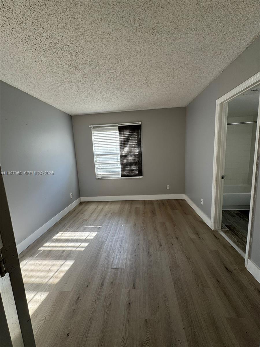 12605 Southwest 54th Court, Unit 12605 Miramar, FL 33027 - Photo 10 of 13 an empty room with wooden floor and windows
