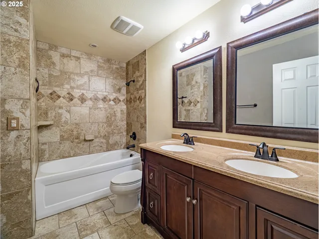 a bathroom with a double vanity sink toilet mirror and bathtub