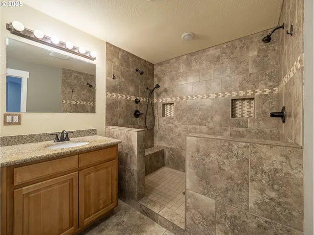 a bathroom with a granite countertop sink a mirror a glass door shower and a mirror