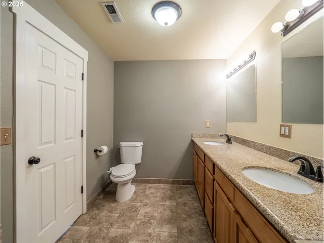a bathroom with a granite countertop sink a toilet and a mirror