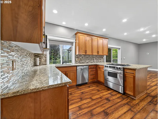 a kitchen with stainless steel appliances granite countertop a sink a stove top oven a counter space and cabinets