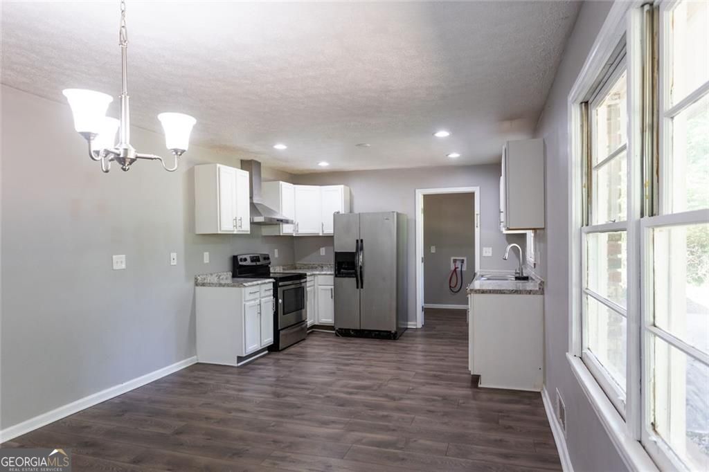 908 East Marable Street Monroe, GA 30656 - Photo 7 of 26 a kitchen with stainless steel appliances kitchen island granite countertop a refrigerator a sink dishwasher a stove and a large window with wooden floor