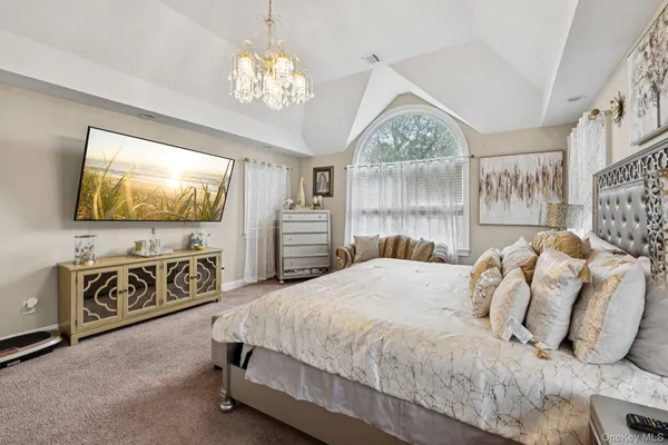 a bedroom with a large bed and a flat tv screen on dresser