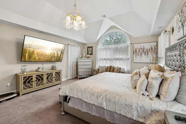 a bedroom with a large bed and a flat tv screen on dresser