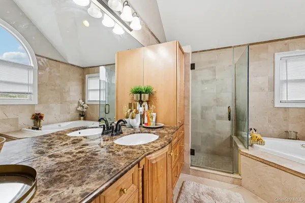 a bathroom with a granite countertop sink a mirror a bathtub and shower