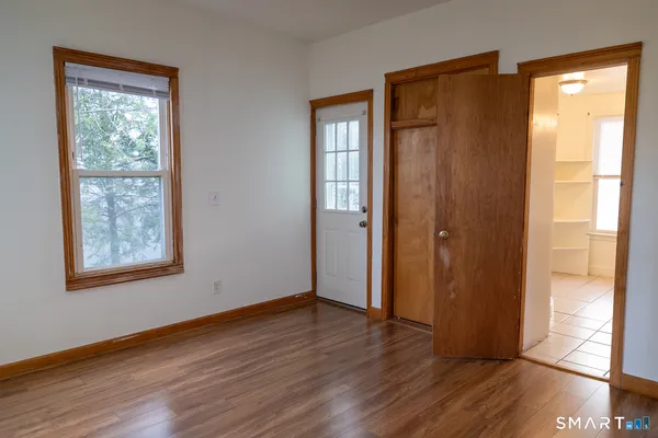 a view of an empty room with wooden floor and a window