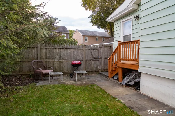 a view of a chair and table in backyard of the house