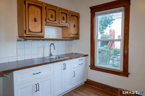 a kitchen with stainless steel appliances granite countertop white cabinets and a large window