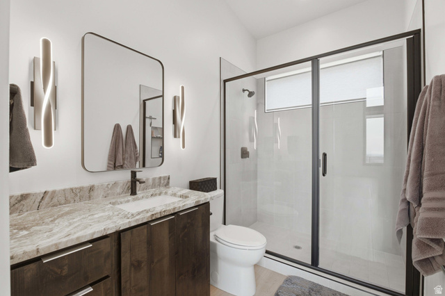 1445 Jacob Road Sandy, UT 84092 - Photo 18 of 52 Custom vanity with stone countertop and integrated sink, modern wall sconces, large framed mirror, and a glass-enclosed shower with dark trim