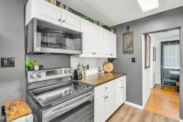 a kitchen with stainless steel appliances kitchen island granite countertop a refrigerator oven a sink dishwasher and white cabinets with wooden floor