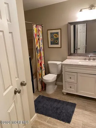 a spacious bathroom with a sink a toilet a mirror a vanity and shower