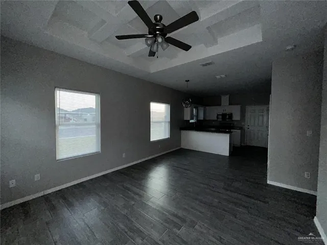 an empty room with wooden floor and a ceiling fan